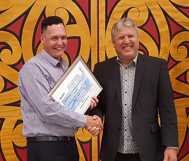 hero - A Office 365 consultant shaking hands with a customer holding an award, in front of a Māori design