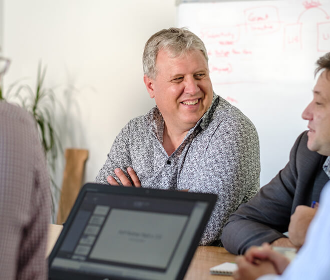 hero - A group of men at a table laughing during a Office 365 training and mentoring session