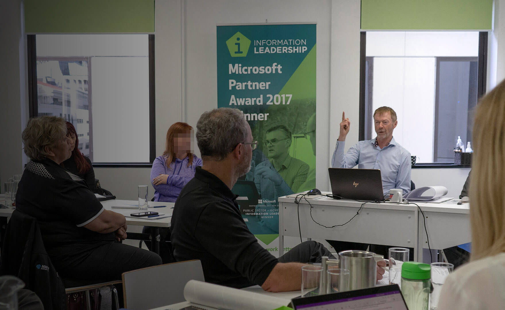 news shadow - Grant Margison gesturing during a Office 365 workshop, in front of a New Zealand Microsoft Partner Award 2017 winner banner