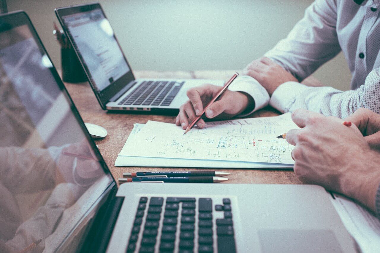 news - Two Office 365 consultants at a desk with laptops, working on a strategy document
