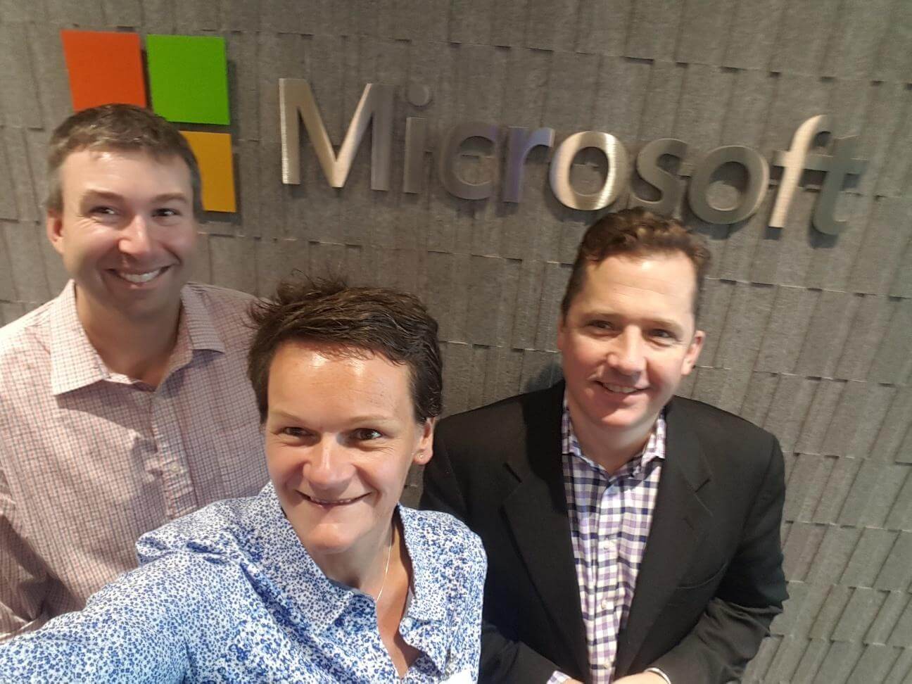 news - Three people taking a selfie in front of a Microsoft logo